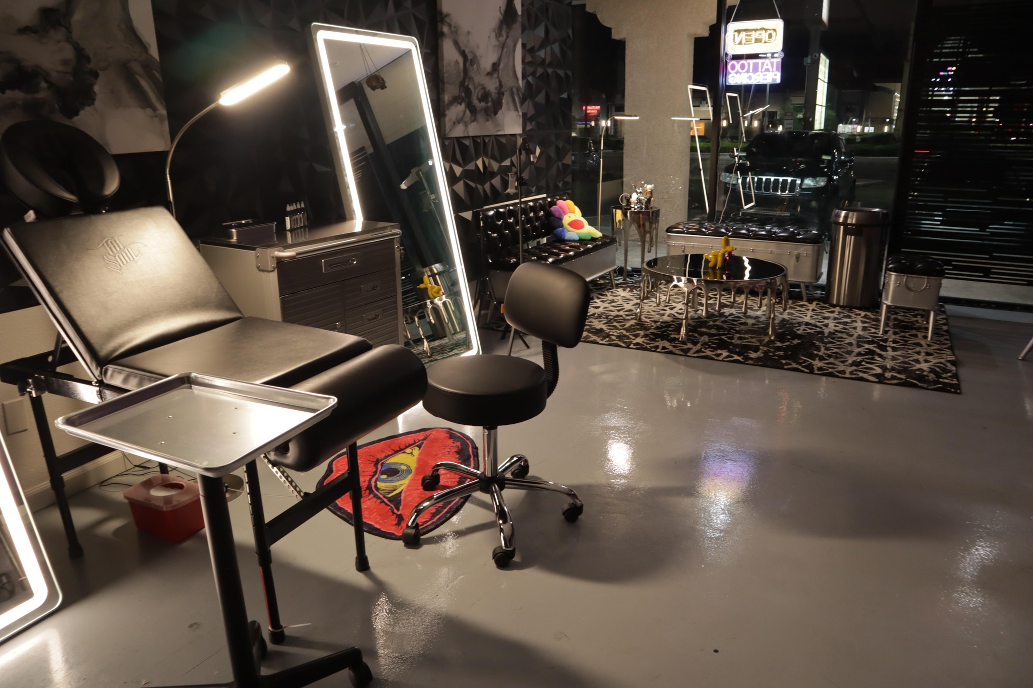 Modern tattoo studio with a chair, workstations, bright lights, and art on the walls.