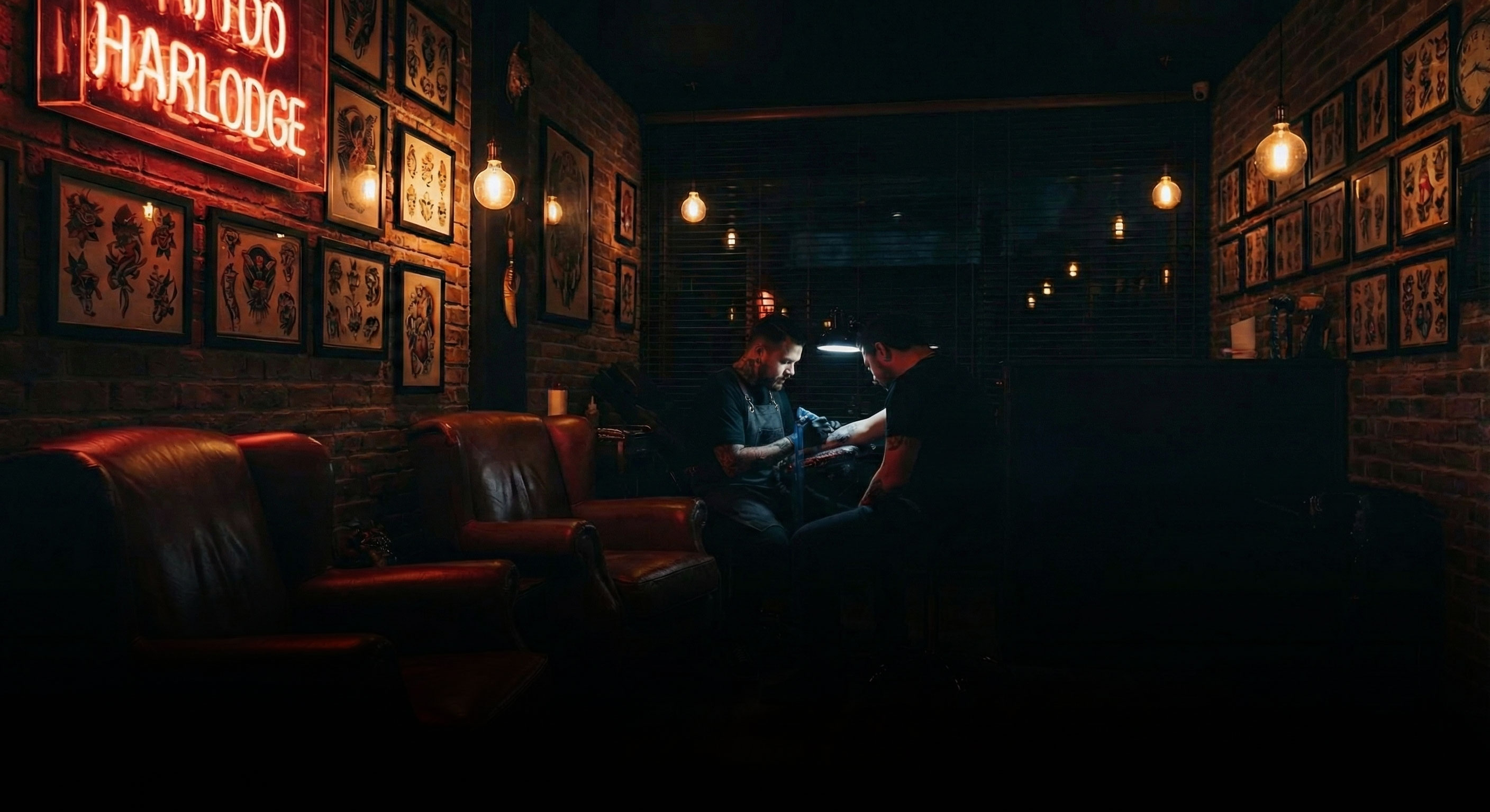 Two people sit in a dimly lit bar with leather seats and framed art on brick walls.